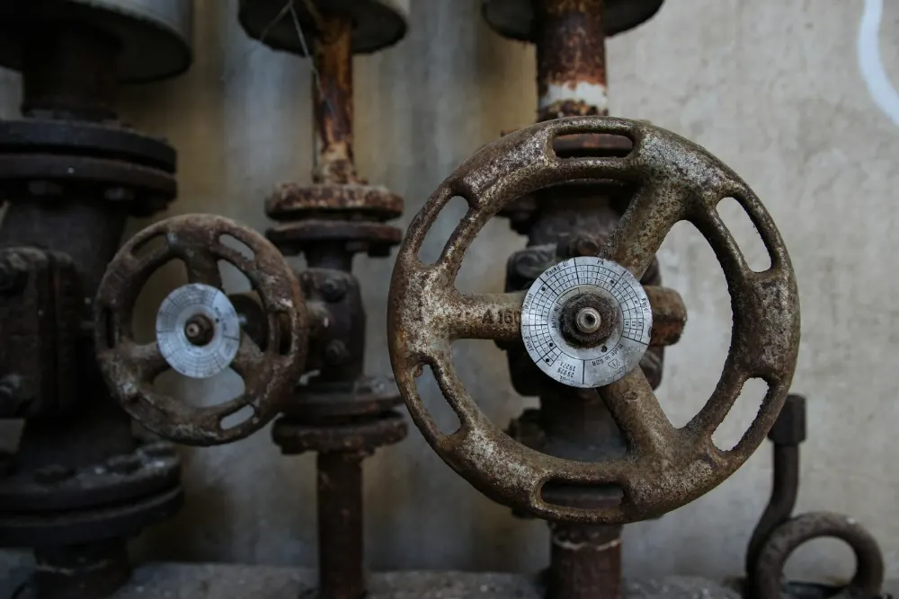 Two rusty gate valves with handwheels on vertical pipework